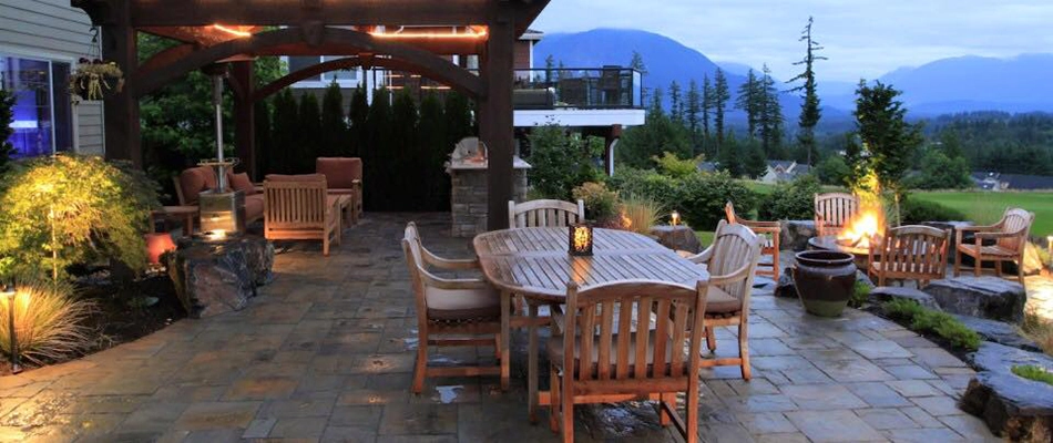 A paved stone patio with wooden furniture and pagoda in Chester Springs , PA.